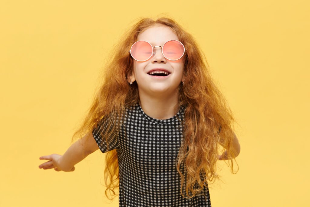 Petite fille avec des lunettes de soleil fantaisistes qui sourit